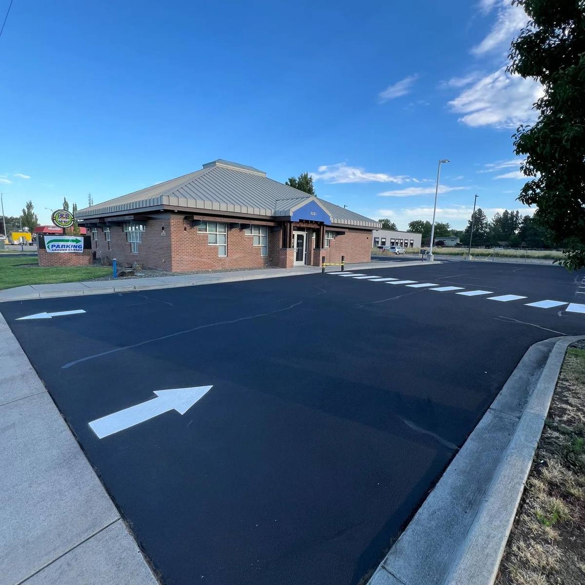 Small commercial building beside a freshly paved asphalt lot with newly painted directional arrows